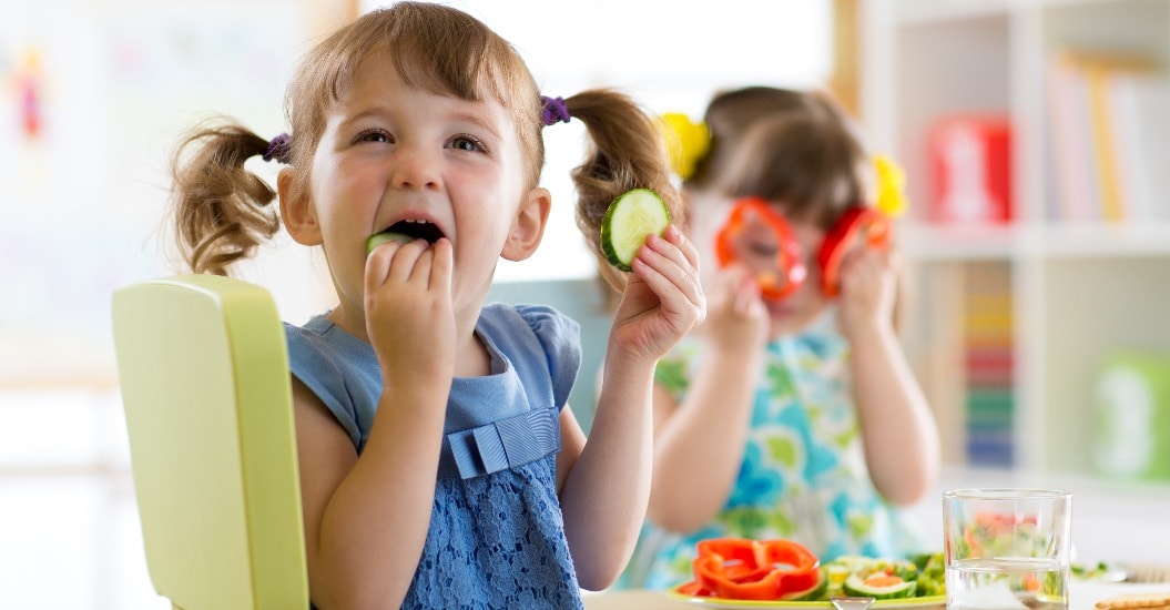 Lachende Kinder essen Gemüse
